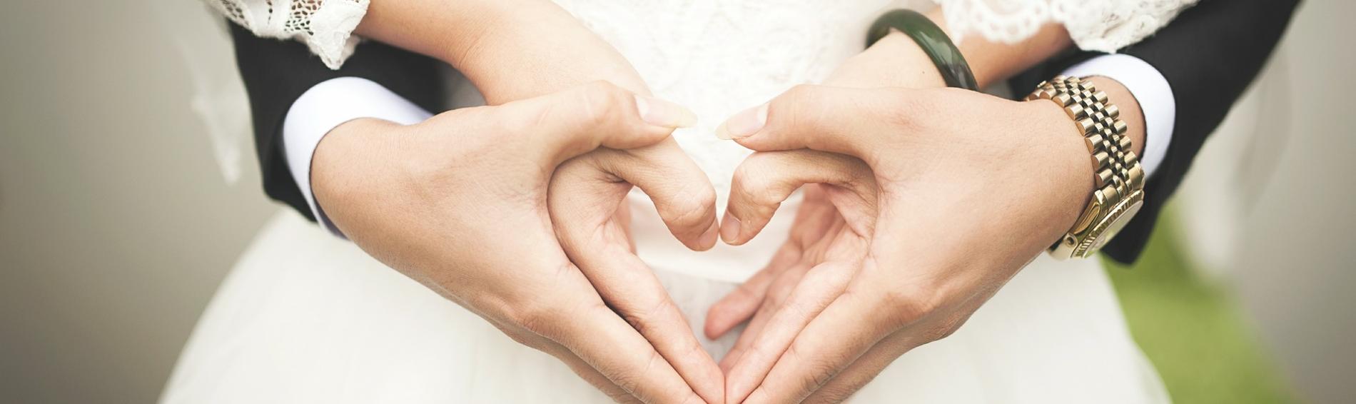 Des mains de mariés formant un coeur