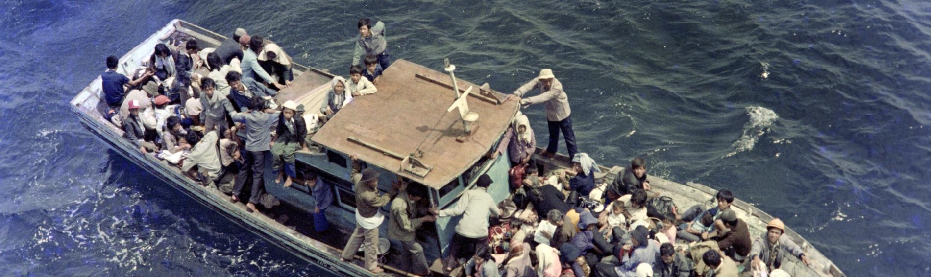 Un bâteau de fortune, rempli à ras bord de réfugiés vietnamiens, sur l'eau.